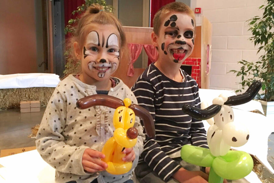 Sculpture de ballons Des enfants avec des maquillage tenant chacun une sculpture de ballons d'une chien et d'une vache.