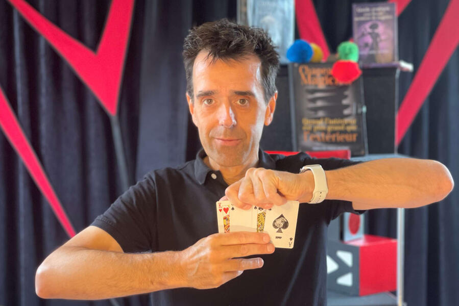 Monsieur Fred réalise une prédiction mentaliste avec des cartes et un album à timbres lors d’un spectacle interactif pour enfants et familles.